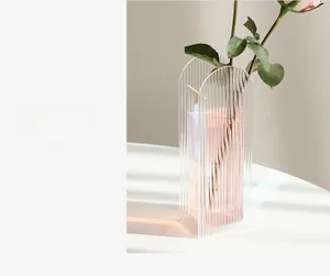 Detail of arched acrylic vase with vertical ribbed texture and a pink rose