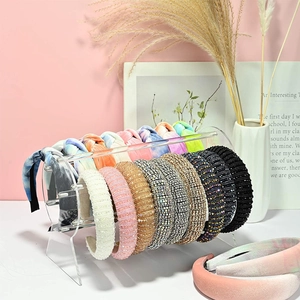 Clear acrylic headband stand displaying assorted crystal and knotted fabric hair hoops