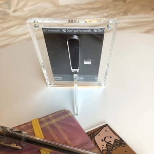 Vertical transparent acrylic frame with stand for instax photos on a desktop workspace