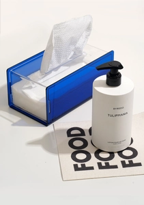 Close-up of a blue transparent acrylic tissue box and a branded hand lotion bottle