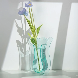 Vaso moderno in acrilico azzurro con bordi ondulati e fiori viola in luce naturale