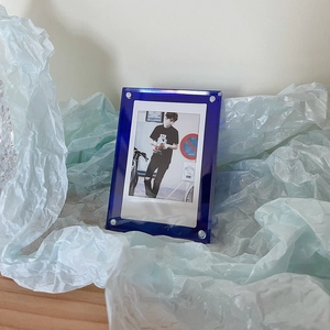 Close-up of blue acrylic 3-inch photo frame with silver metal screws on blue paper