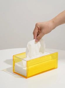 Detail of translucent yellow acrylic tissue box with orange edges on white table