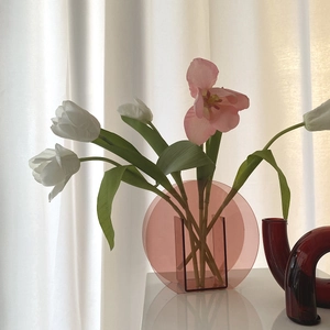 Runde rosa Acrylblumenvase auf dem Tisch mit weichem Fensterlicht im Detail