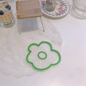 Détail d'un dessous de verre en acrylique vert en forme de fleur, fini transparent