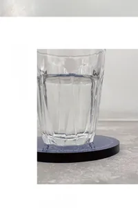 Close-up of a striped glass on a blue acrylic coaster with printed circular typography
