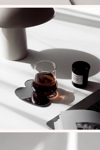 Macro shot of a heart-shaped acrylic mirror coaster with reflective finish and glass cup