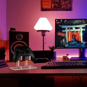 Clear acrylic game controller wall mount stand on desk with gaming setup background