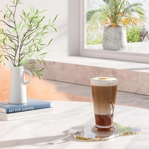 Clear glass coffee cup with handle on a gold-rimmed acrylic coaster for table decor