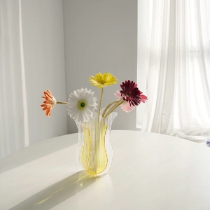 Moderne gewellte Acryl-Vase mit gelben Streifen und bunten Gerbera-Blumen