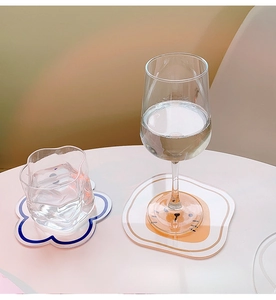 Detail of acrylic cartoon coasters with wavy blue border and egg-shaped orange design