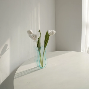 Moderne hellblaue gewellte Acrylvase mit weißen Tulpen als minimalistische Wohndeko
