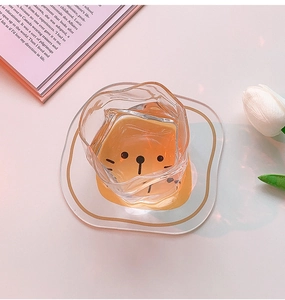 Close-up of wavy edge glass cup with cute cat face bottom and gold-rimmed coaster