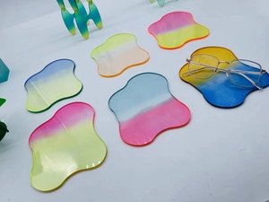 Close-up of irregular wave gradient acrylic coasters in vibrant pink and blue colors