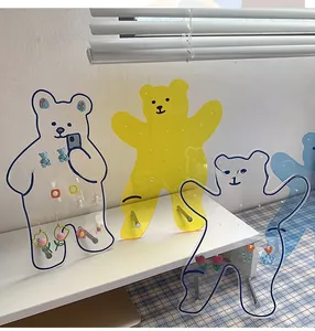 Detail view of acrylic bear jewelry stand holding earrings and necklaces on a desk