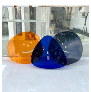 Close-up of three translucent acrylic coasters with minimalist smiley faces in orange and blue