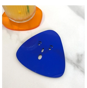 Detail of blue acrylic coaster with quirky face cutout on white marble table