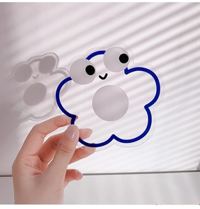 Close-up of blue flower-shaped acrylic phone grip with cute cartoon face and soft shadow