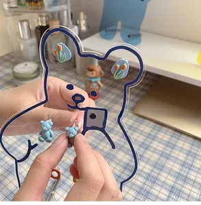 Close-up of cute blue bear and tulip earrings on a transparent acrylic bear jewelry stand