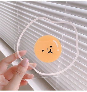 Detailed view of a poached egg acrylic coaster held against a sunlit shutter background