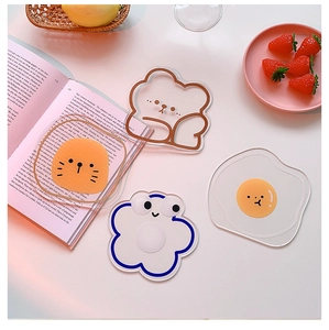 Detail view of cute acrylic coasters in cartoon bear, cat, and flower shapes on a white desk