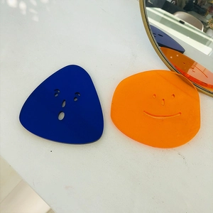 Minimalist acrylic coasters with face cutouts in vibrant blue and orange finishes