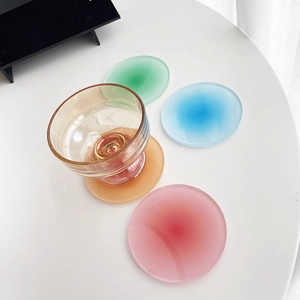 Artistic round acrylic coasters with sunset gradient colors and transparent glassware