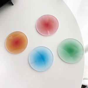 Flat lay of four colorful round acrylic coasters with gradient sunset colors on white desk