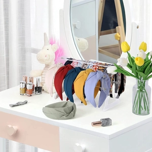 Set of colorful fabric headbands and acrylic display stand on a bright white vanity table