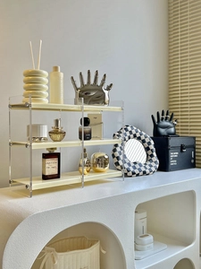 Detailed close-up of a three-tier cream acrylic organizer rack with clear side panels