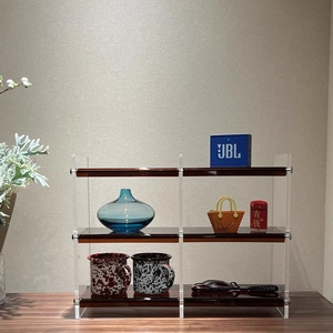 Close-up of three-tier acrylic cosmetic organizer with transparent brown shelves on wood