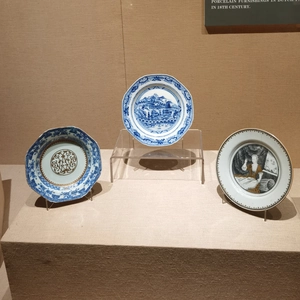 Three assorted decorative porcelain plates shown on clear acrylic display stands