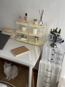 Three-tier acrylic desk organizer with cream shelves in a sunlit home office setting