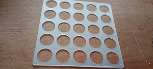 Close-up of a 25-hole clear acrylic storage rack for vinyl rolls on a wood background