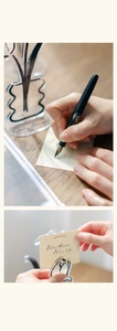 Detail of acrylic tulip card holder with minimalist black line art on wooden desk