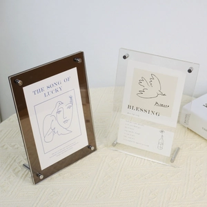 Close-up of minimalist acrylic picture frames with metallic screw stands and art cards