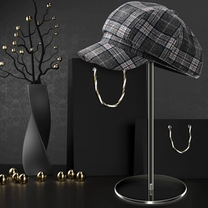 Detail of vintage plaid newsboy cap on silver metal stand with elegant decor accessories