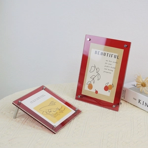 Detail of red acrylic photo frames with metal screws on woven fabric surface