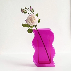 Macro detail of the wave-shaped magenta acrylic vase with semi-transparent modern design