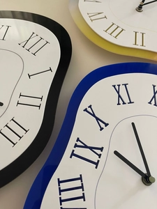 Detail of surreal melting wall clocks with Roman numerals in black, blue and yellow