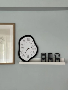 Detail of creative melting wall clock in Dali style with roman numerals on shelf