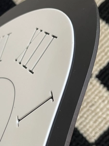 Detailed macro view of laser-cut Roman numerals and matte finish on a modern wall clock