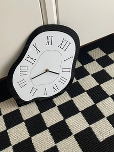 Detail of melting wall clock with black Roman numerals and artistic distorted frame