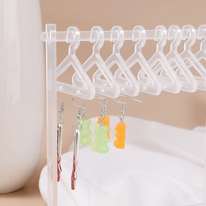 Macro view of transparent acrylic earring organizer with mini clothes hangers and charms