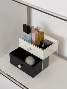 Détail d'un organisateur en acrylique à deux niveaux avec tiroirs noir et blanc et perles