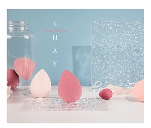 Artistic layout of Morandi pink beauty blenders on a water ripple glass surface