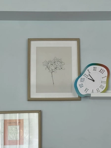 Detail of melting wall clock with rainbow gradient edge and Roman numerals on blue wall