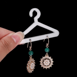 Vintage gold metal earrings with green beads and flower clusters shown on acrylic stand
