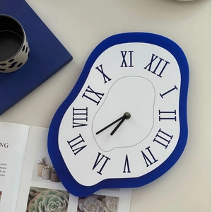 Melting Dali style wall clock in cobalt blue with Roman numerals on a beige surface