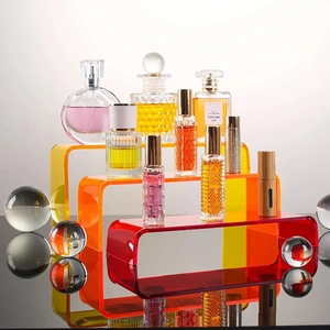 Détail d'un présentoir en acrylique coloré avec flacons de parfum en verre variés